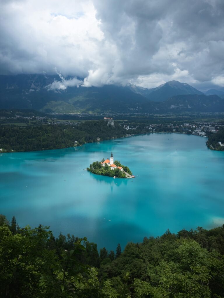 Stunning aerial capture of Lake Bled with its iconic island and church surrounded by turquoise waters and mountainous terrain.